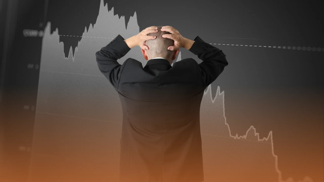 Muž chytajúci sa za hlavu pred padajúcim grafom
