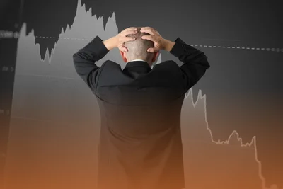 Muž chytajúci sa za hlavu pred padajúcim grafom